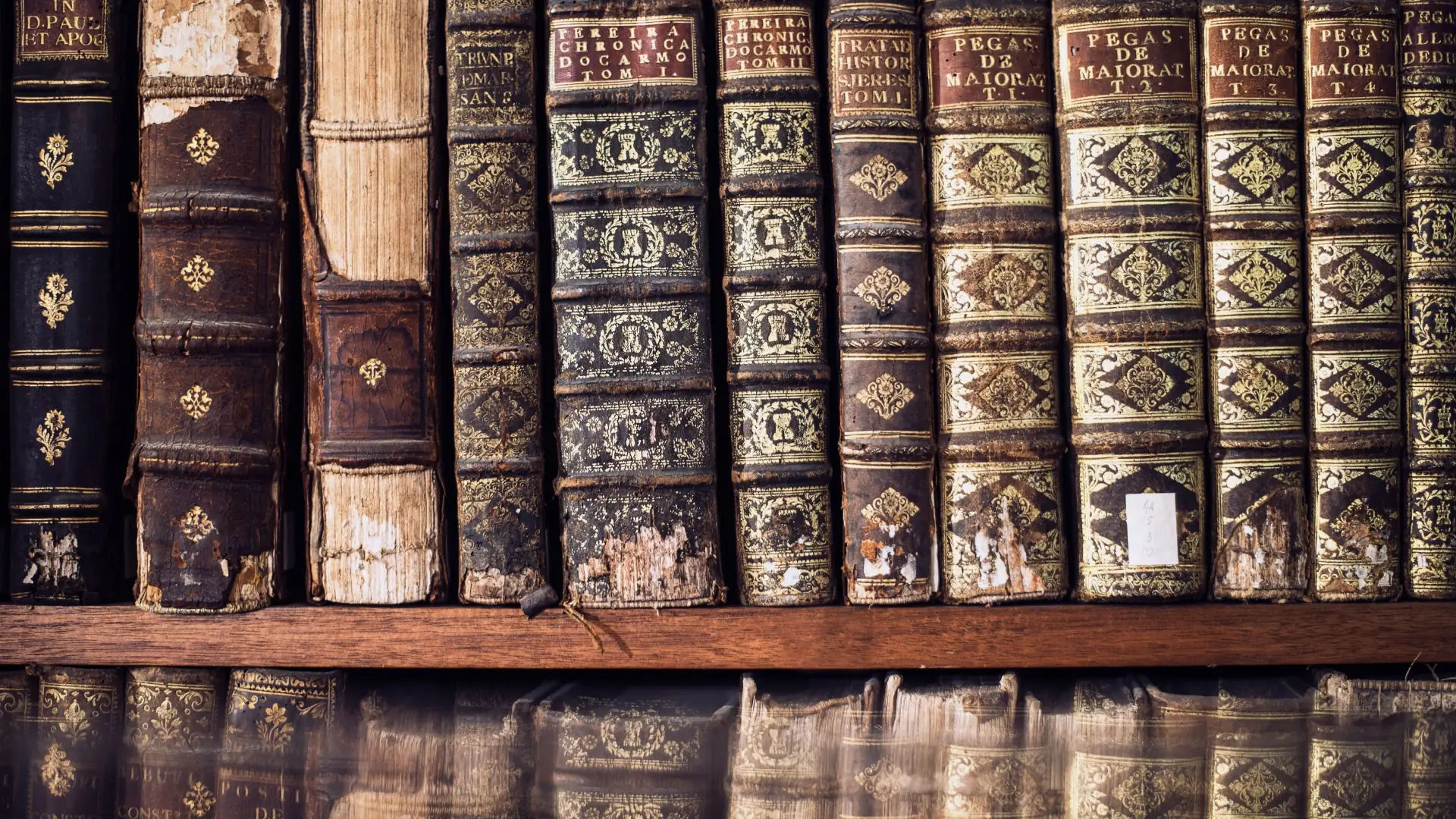 A row of dusty, vintage leather-bound books on a dark wooden shelf, symbolizing outdated and overly complex SaaS product documentation that users fail to consult.